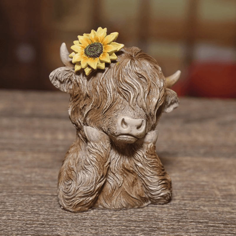 Highland cow ornament with sunflower on a wooden tabletop, rustic lifestyle scene, approx. 9 x 11cm.
