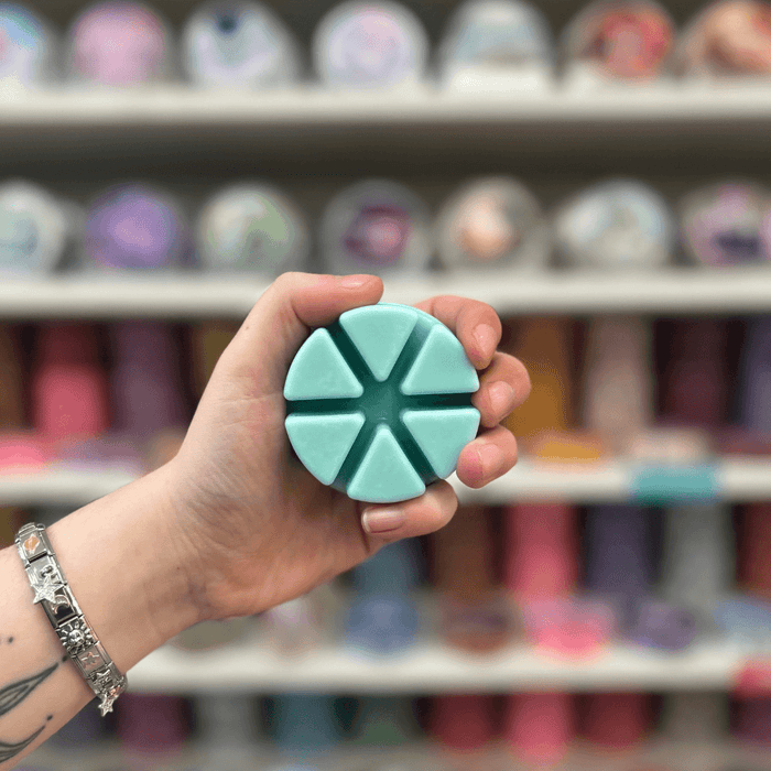 Sweet Nothings wax melt segments held in hand with colourful wax melt display in the background