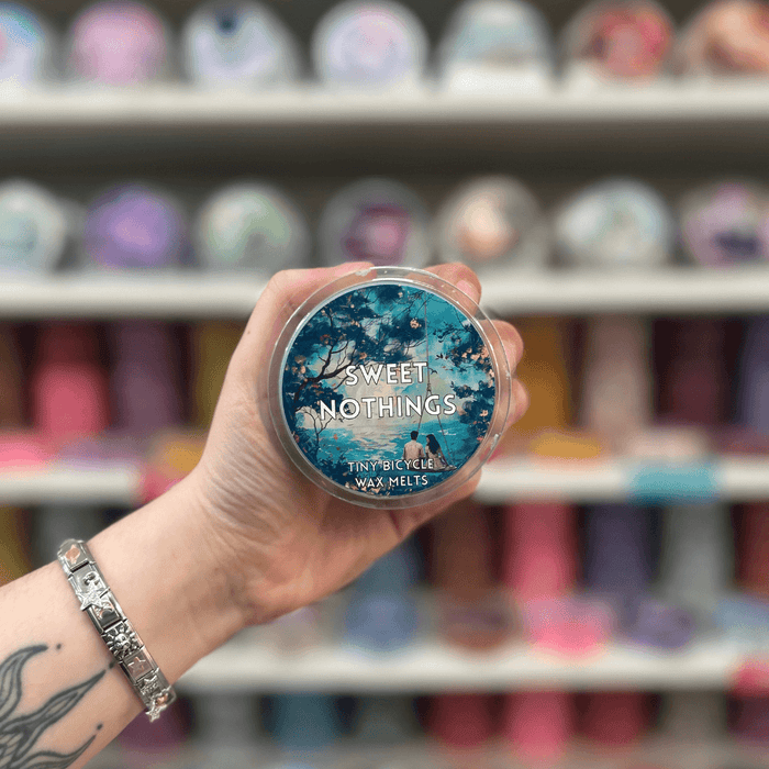 Sweet Nothings wax melt pot held in hand with colourful wax melt display in the background
