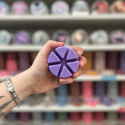 Sweetpea wax melt segments held in hand with colourful wax melt display in the background