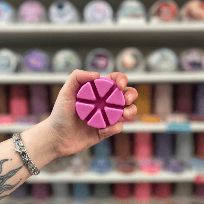 The Comforter wax melt segments held in hand with colourful wax melt display in the background