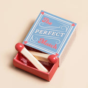 Open matchbox with The Perfect Match lid and two mini ceramic match tokens inside