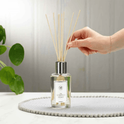 Natural rattan diffuser reeds being placed into The Scented Home reed diffuser