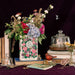 The Secret Garden book vase filled with flowers on a cosy tabletop with stacked books.