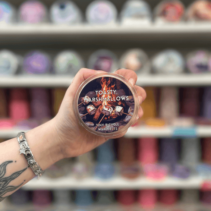 Toasty Marshmallows wax melt pot held in hand with colourful wax melt display in the background