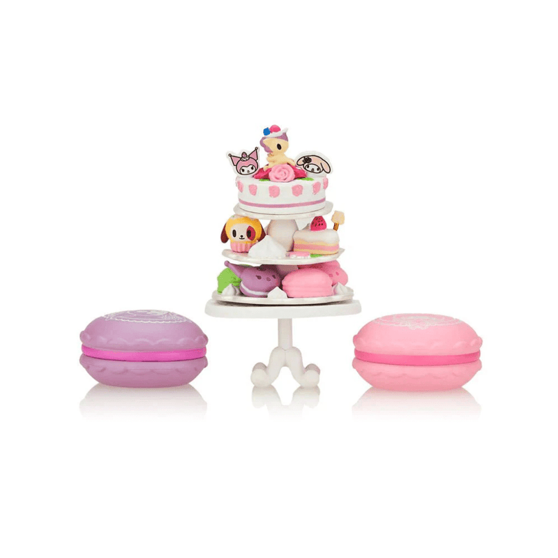 Tokidoki collectible chaser play-set: tiered Garden Tea Cakes stand piled with miniature Sanrio sweets, flanked by two macaron boxes.
