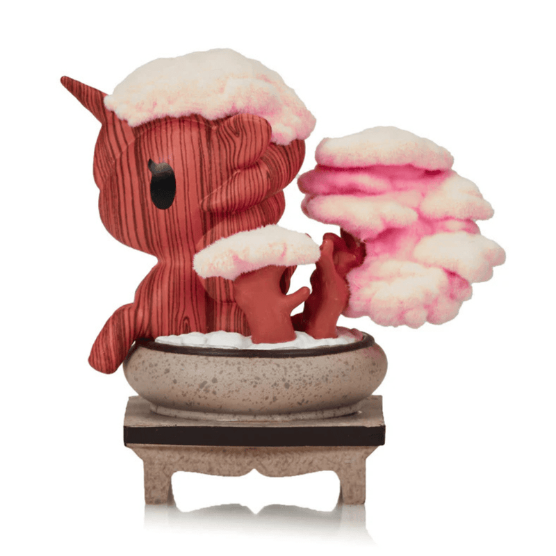 Left profile of Tokidoki Cherry Blossom Serenity collectible – wood-textured Unicorno with flocked pink cherry blossoms in stone bonsai dish.

