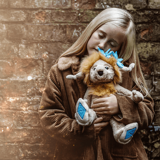 Topaz Blu Charlie Bears Bearhouse crystal troll plush being cuddled outdoors, showing the blue crystal accents and soft golden fur