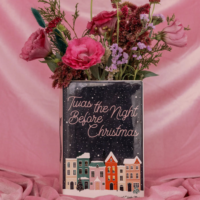 Close-up of Twas the Night Before Christmas book vase with bright flowers on pink velvet backdrop