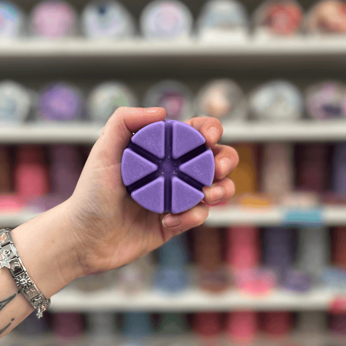 Twilight Rainfall wax melt segments held in hand with colourful wax melt display in the background