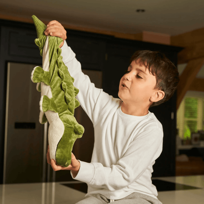 Child holding Warmies Alligator heatable plush toy