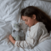 Child cuddling Warmies Armadillo heatable plush toy in bed