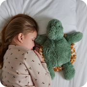 Child cuddling Warmies turtle plush in bed

