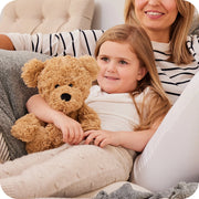 Child cuddling Warmies curly bear plush on sofa

