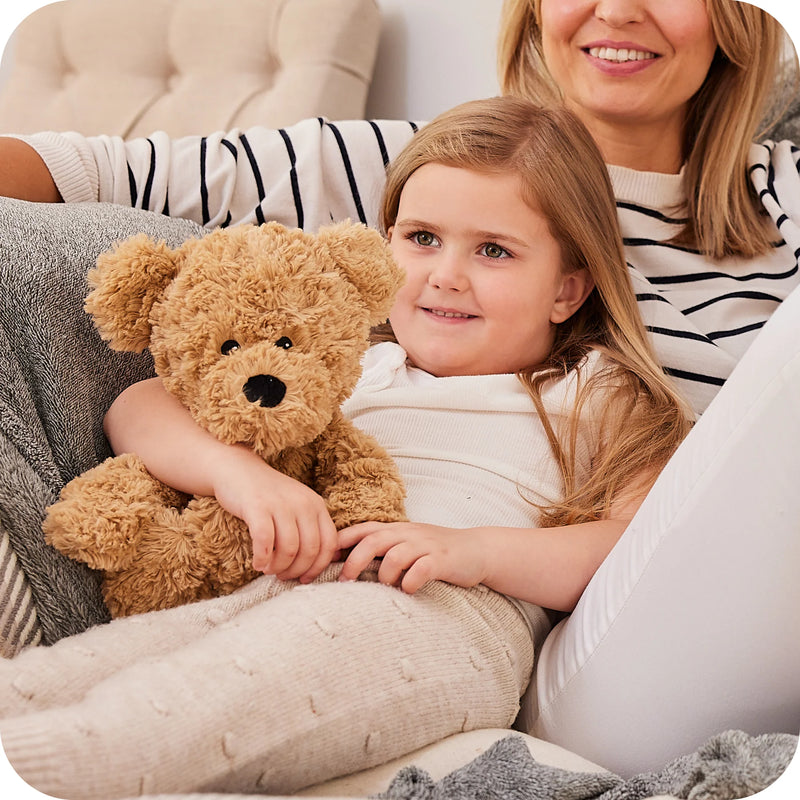 Child cuddling Warmies curly bear plush on sofa

