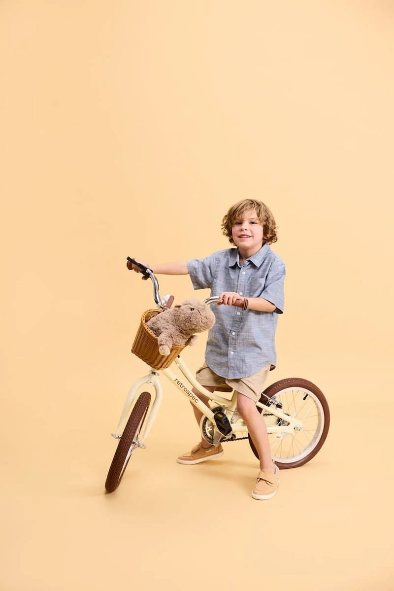 Child riding a bike with the Warmies Capybara Plush Toy in the basket.