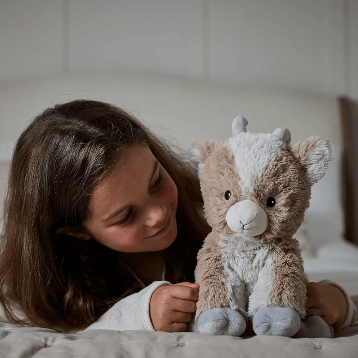 Warmies Goat plush toy in a bedroom lifestyle image