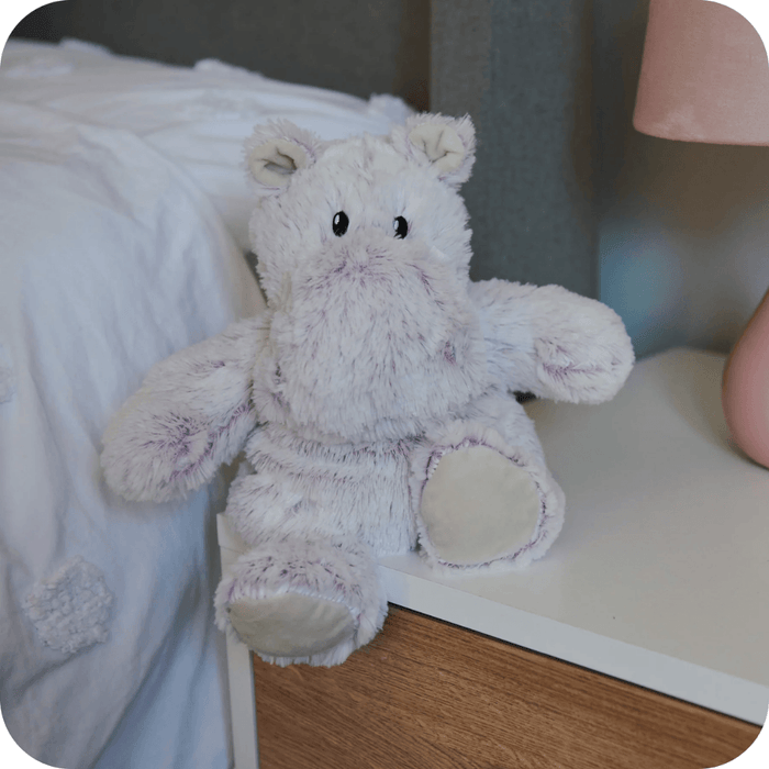 Warmies Marshmallow Hippo plush toy sitting on a bedside table