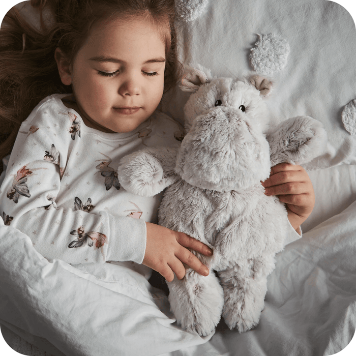 Child holding Warmies Marshmallow Hippo heatable plush toy