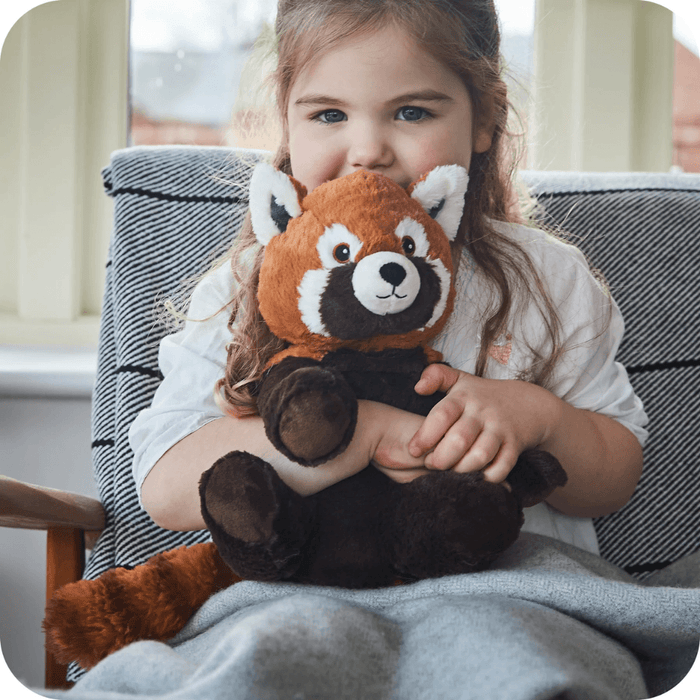 Child holding Warmies Red Panda heatable plush toy