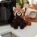 Warmies Red Panda plush toy beside a microwave on a kitchen counter
