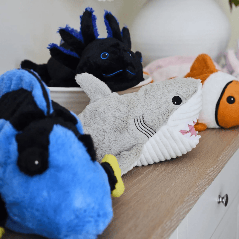 Warmies Shark plush toy displayed on a shelf with sea creature plush toys
