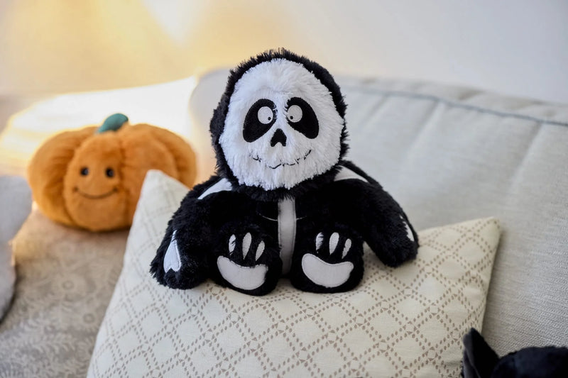 Warmies Skeleton plush toy on a cushion with Halloween pumpkin plush