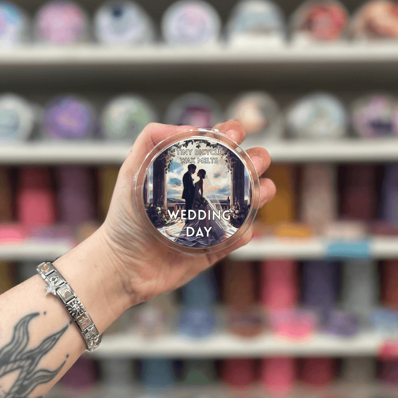 Wedding Day wax melt pot held in hand with colourful wax melt display in the background