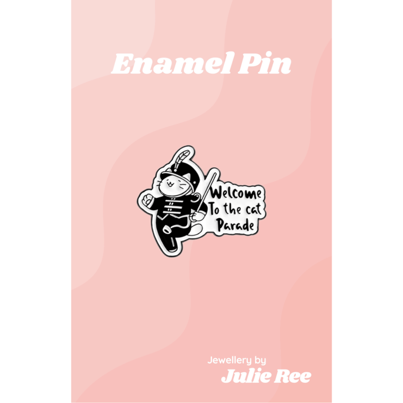 Black and white enamel pin of a marching band cat with the text Welcome to the cat parade