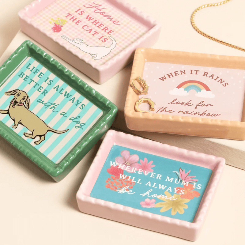 Pink ceramic trinket dish with Home Is Where The Cat Is design shown in a styled flat lay with other mini trinket dishes.