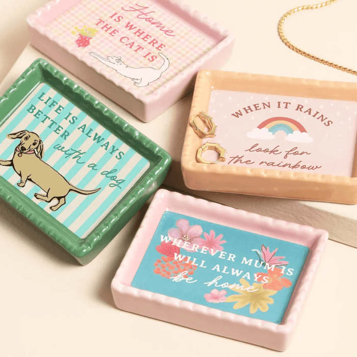 Pink ceramic trinket dish with Home Is Where The Cat Is design shown in a styled flat lay with other mini trinket dishes.