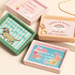 Pink ceramic trinket dish with Home Is Where The Cat Is design shown in a styled flat lay with other mini trinket dishes.