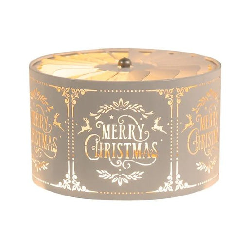 White and gold carousel candle shade with ‘Merry Christmas’ and reindeer design, glowing warmly above a candle.

