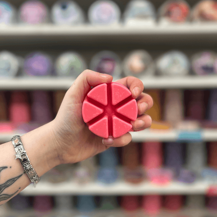 Wild Berry Grove wax melt segments held in hand with colourful wax melt display in the background