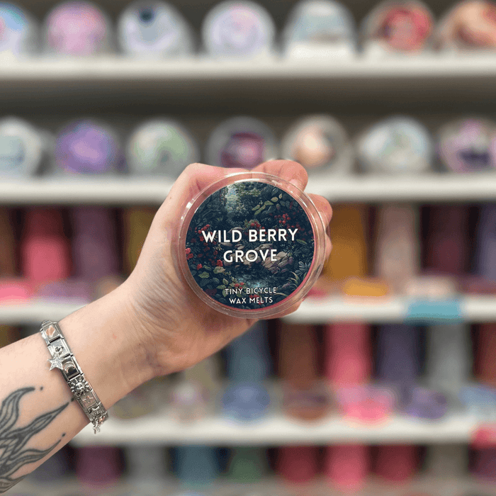 Wild Berry Grove wax melt pot held in hand with colourful wax melt display in the background