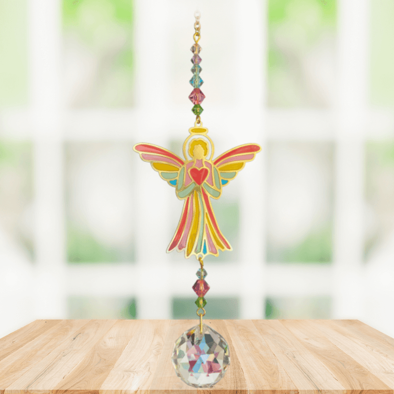Handmade angel-heart crystal suncatcher displayed on a wooden table in a bright window

