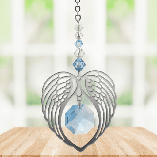 Aquamarine angel wing heart crystal suncatcher hanging in a bright window
