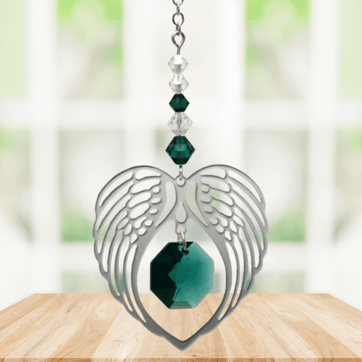 Emerald angel wing heart suncatcher with crystals hanging in a bright window