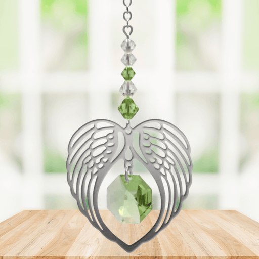Peridot angel wing heart crystal suncatcher hanging in a bright window
