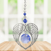 Sapphire angel wing heart suncatcher with crystals hanging in a bright window