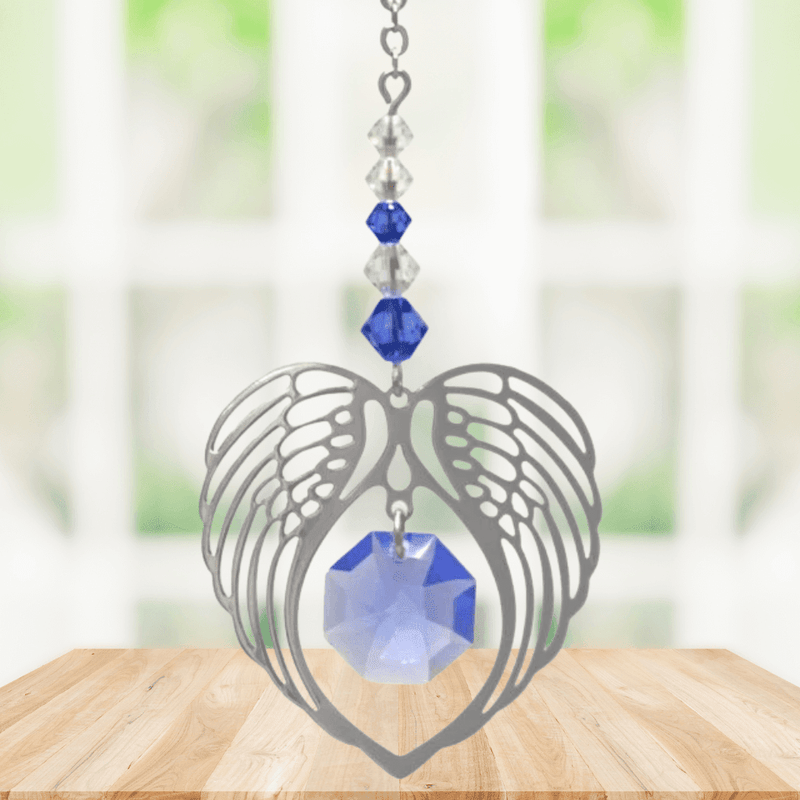 Sapphire angel wing heart suncatcher with crystals hanging in a bright window