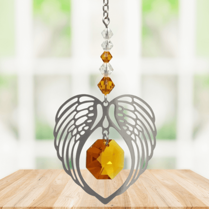 Topaz angel wing heart suncatcher with crystal octagon hanging in a bright window
