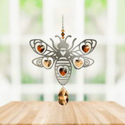 Handmade Bee Autumn Gold crystal suncatcher displayed on a wooden table in front of a bright window

