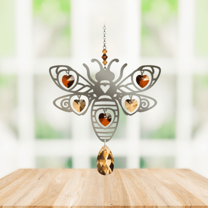 Handmade Bee Autumn Gold crystal suncatcher displayed on a wooden table in front of a bright window

