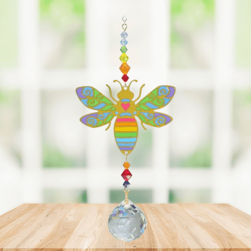 Handmade Bee Rainbow crystal suncatcher displayed on a wooden table in front of a bright window

