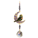 Blackbird Moonlight Crystal Suncatcher hanging in garden sunlight – blackbird on purple crescent moon with amethyst beads and 20 mm crystal ball rainbowing the air.
