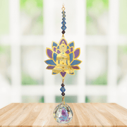 Buddha Moonlight Crystal Suncatcher hanging in bright window light – gold Buddha within purple-teal lotus, sapphire bead run and 20 mm crystal ball scattering rainbows.
