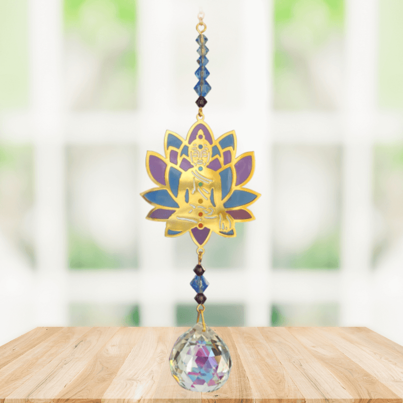 Buddha Moonlight Crystal Suncatcher hanging in bright window light – gold Buddha within purple-teal lotus, sapphire bead run and 20 mm crystal ball scattering rainbows.
