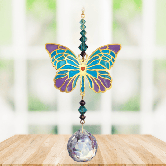 Butterfly Iris Crystal Suncatcher hanging in a bright window; jewel-tone butterfly motif, faceted teal–amethyst beads and sparkling crystal ball.
