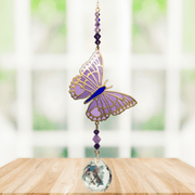 Butterfly Purple Emperor Crystal Suncatcher hanging in a sunny window; lavender-purple enamel wings, faceted violet beads and sparkling crystal ball.
